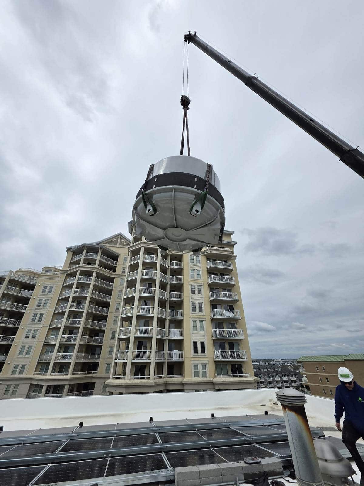 Rooftop equipment lift with the boom set high over the building