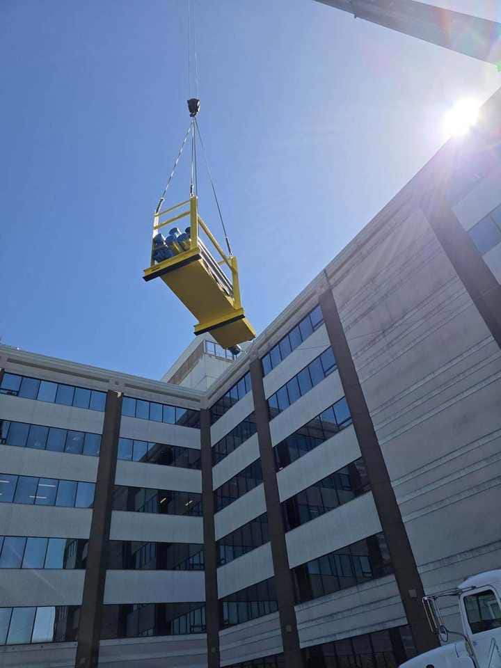 Yellow equipment skid lifted between urban buildings