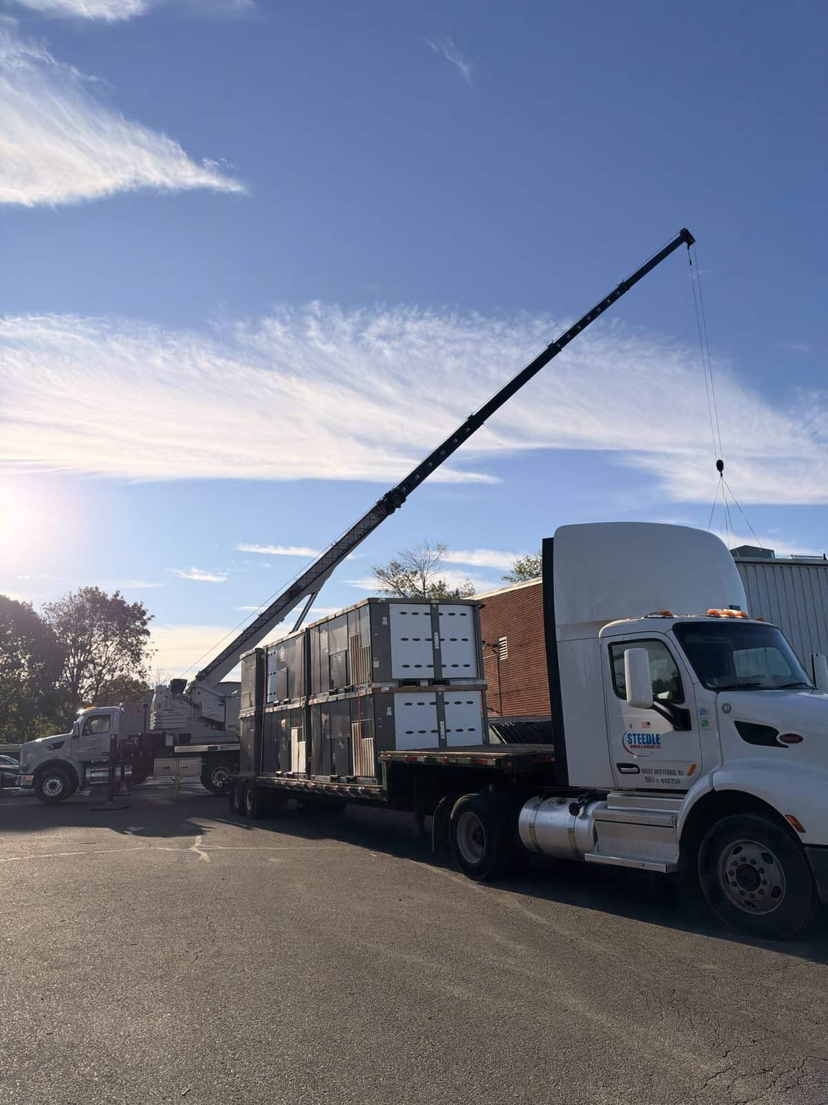 Steedle tractor and flatbed loaded with rooftop HVAC units, boom truck behind, in Egg Harbor Township, NJ