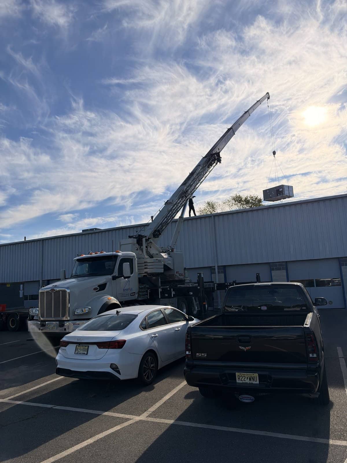 Steedle boom truck with the boom up and a rooftop unit near the roof in Egg Harbor Township, NJ