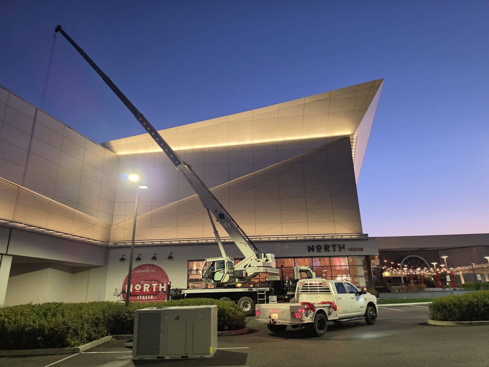 Steedle truck crane with the boom up under a dark blue pre-dawn sky, lights still on, at the King of Prussia mall in King of Prussia, PA