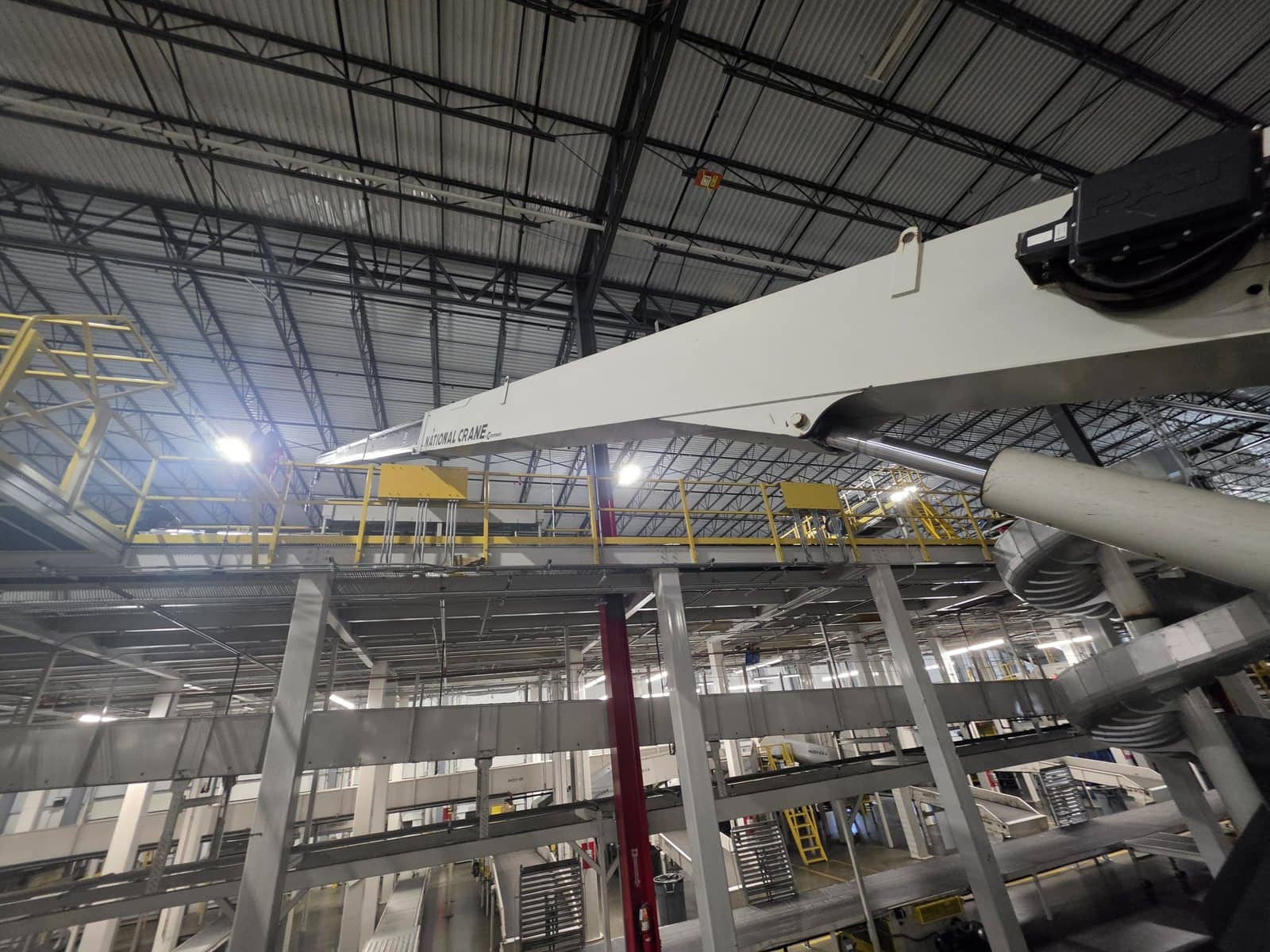National Crane boom reaching past a mezzanine and overhead steel inside a distribution facility in East Brunswick, NJ