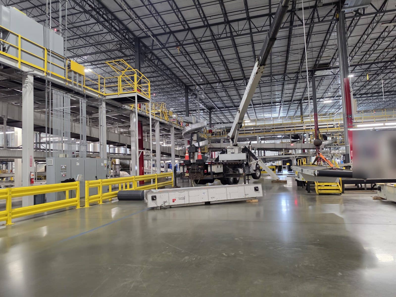 Steedle truck crane set up on the floor of a distribution facility in East Brunswick, NJ with conveyor sections being swapped under the mezzanine