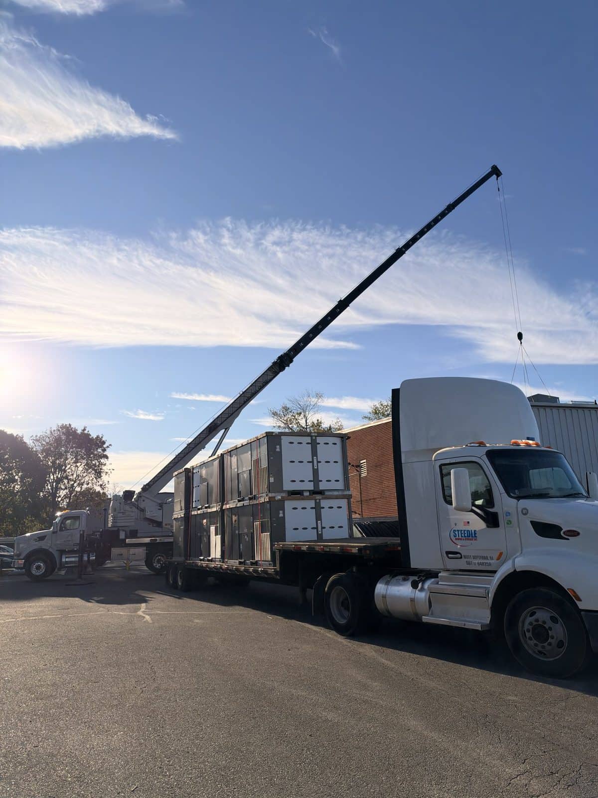 Steedle tractor and flatbed loaded with rooftop HVAC units, boom truck behind, in Egg Harbor Township, NJ
