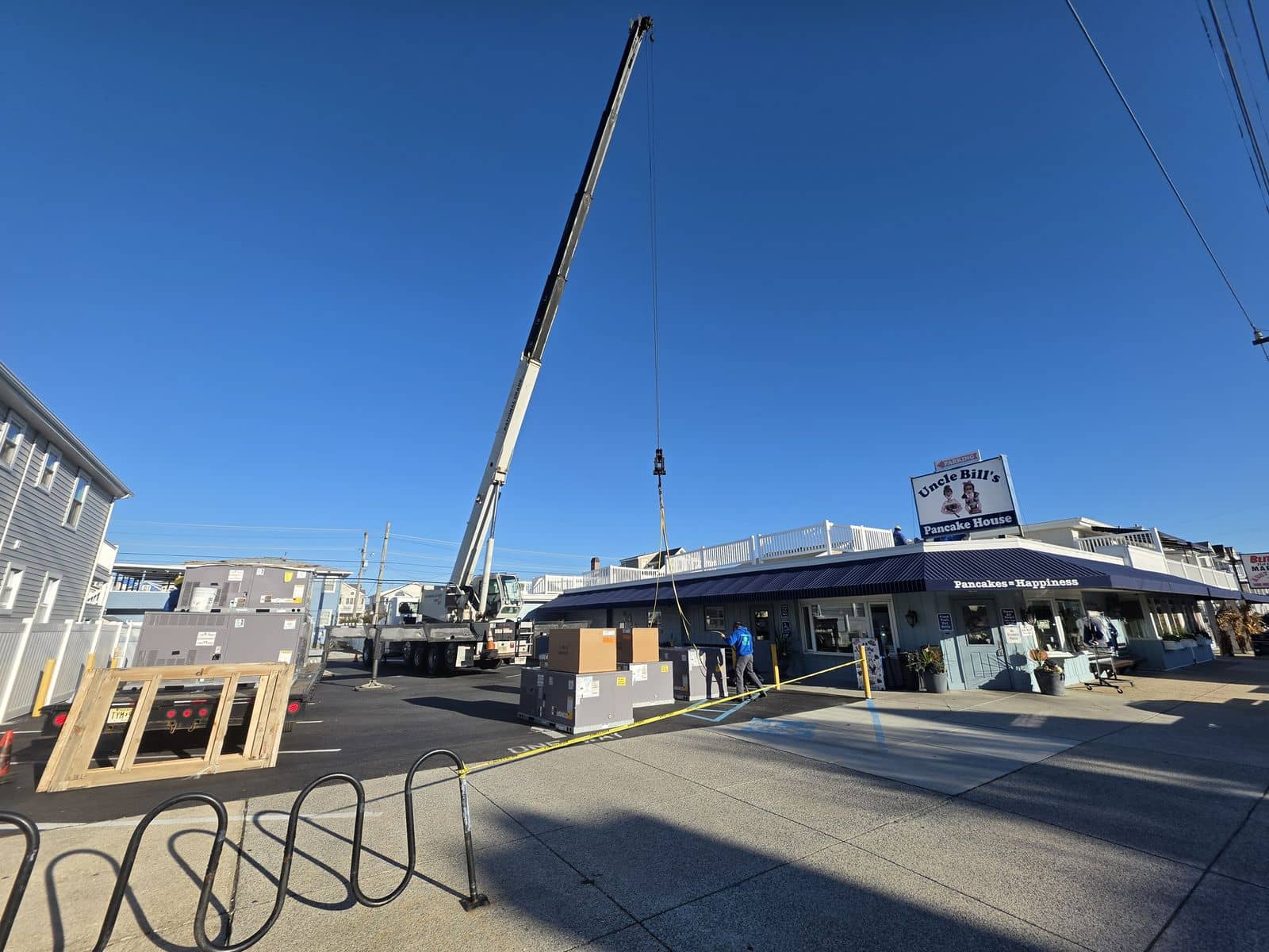Steedle truck crane with the boom up beside a breakfast restaurant in Ocean City, NJ, with new rooftop units on the ground waiting to be lifted