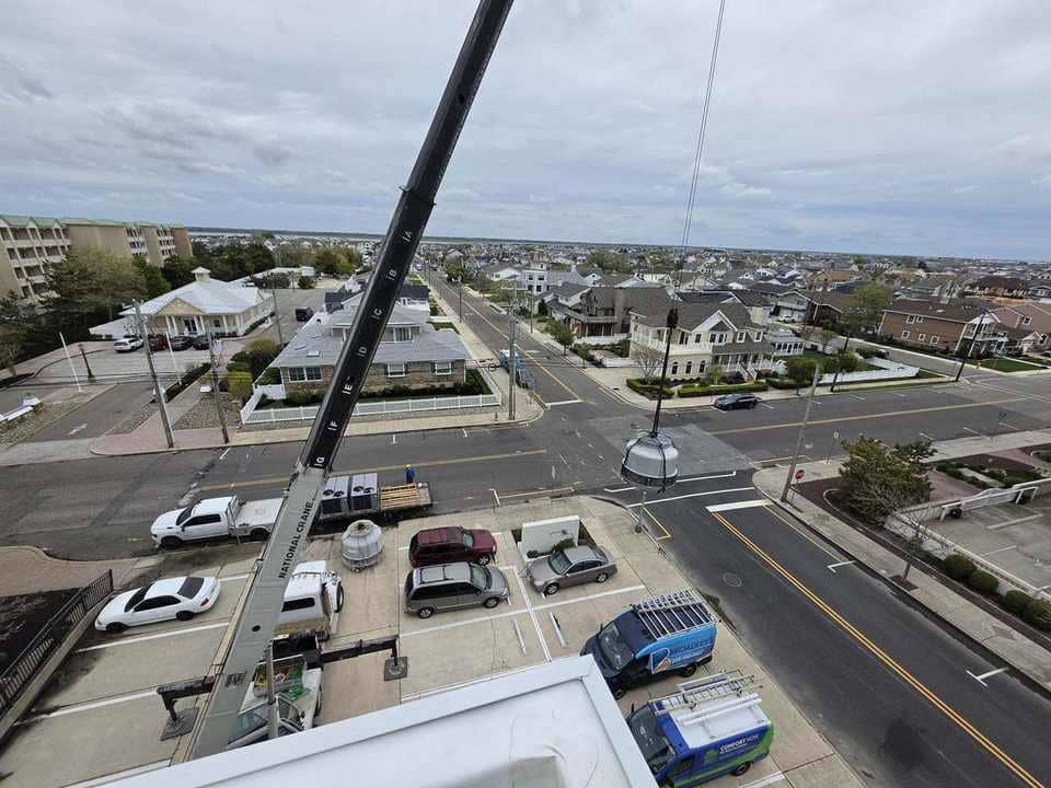 Truck crane lifting a cooling-tower section toward a rooftop