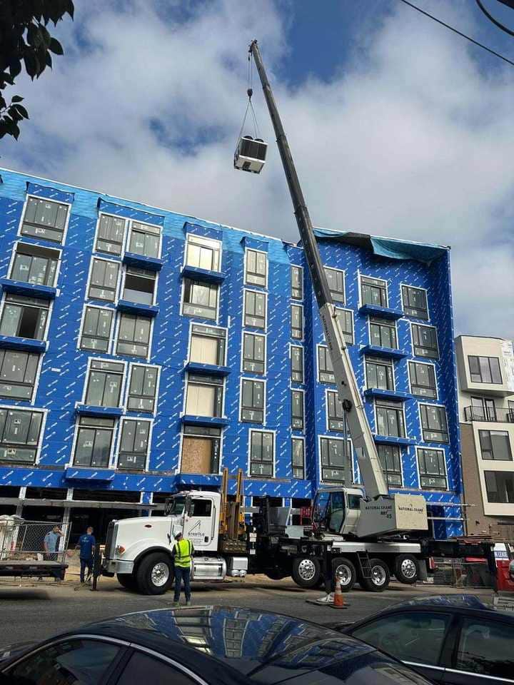 Steedle crane setting HVAC equipment on a multi-story building