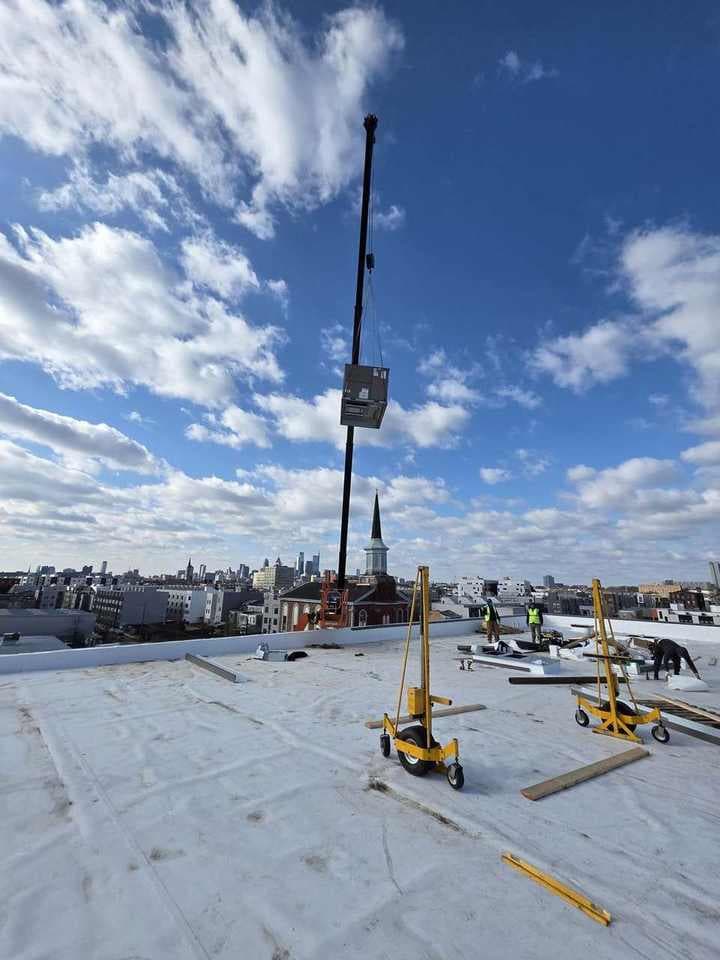 Steedle crane boom set on a rooftop job overlooking the city